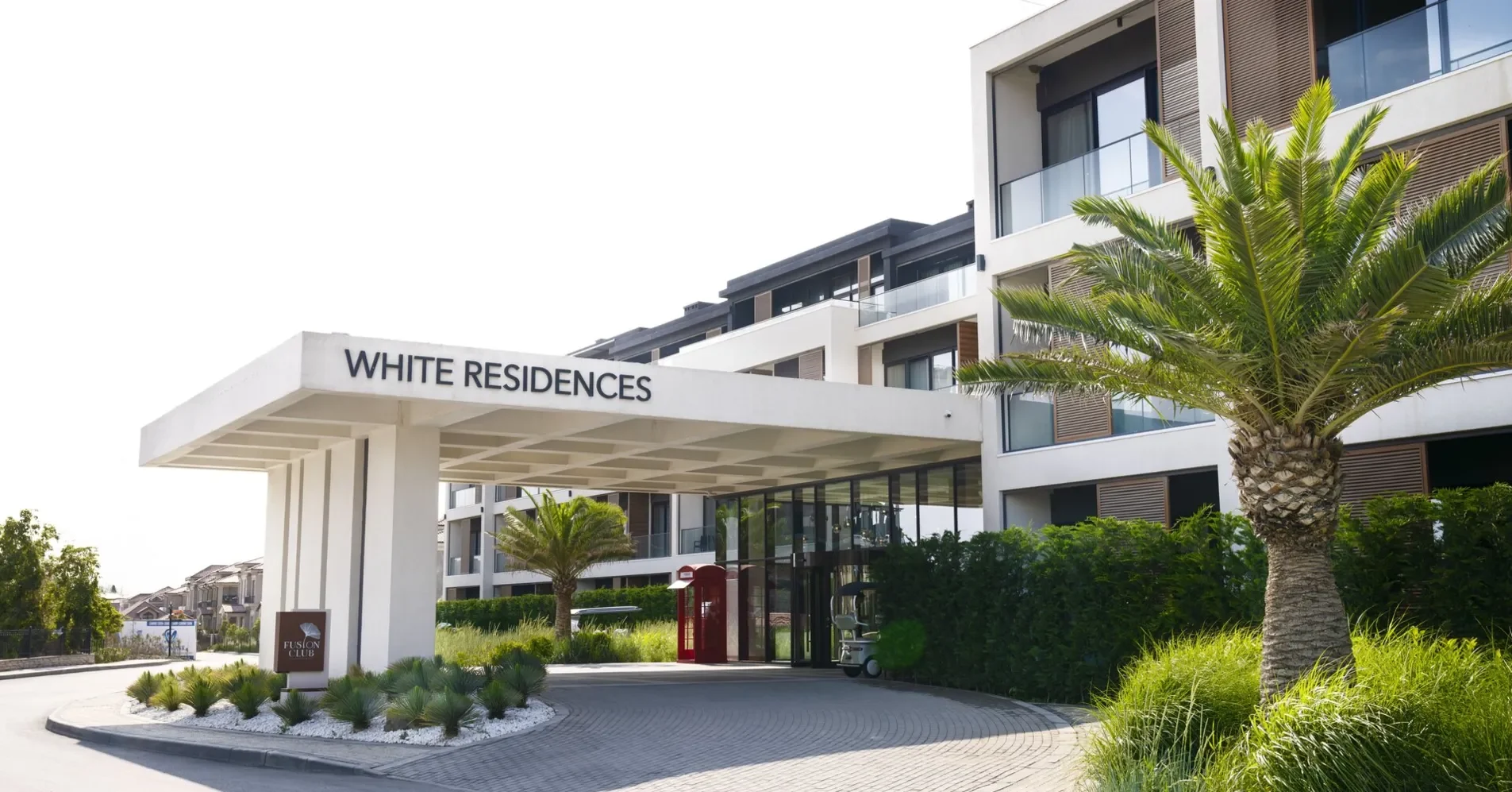 Въезд в White Residences: козырёк с надписью, за ним корпус — White Cafe на первом этаже этого здания